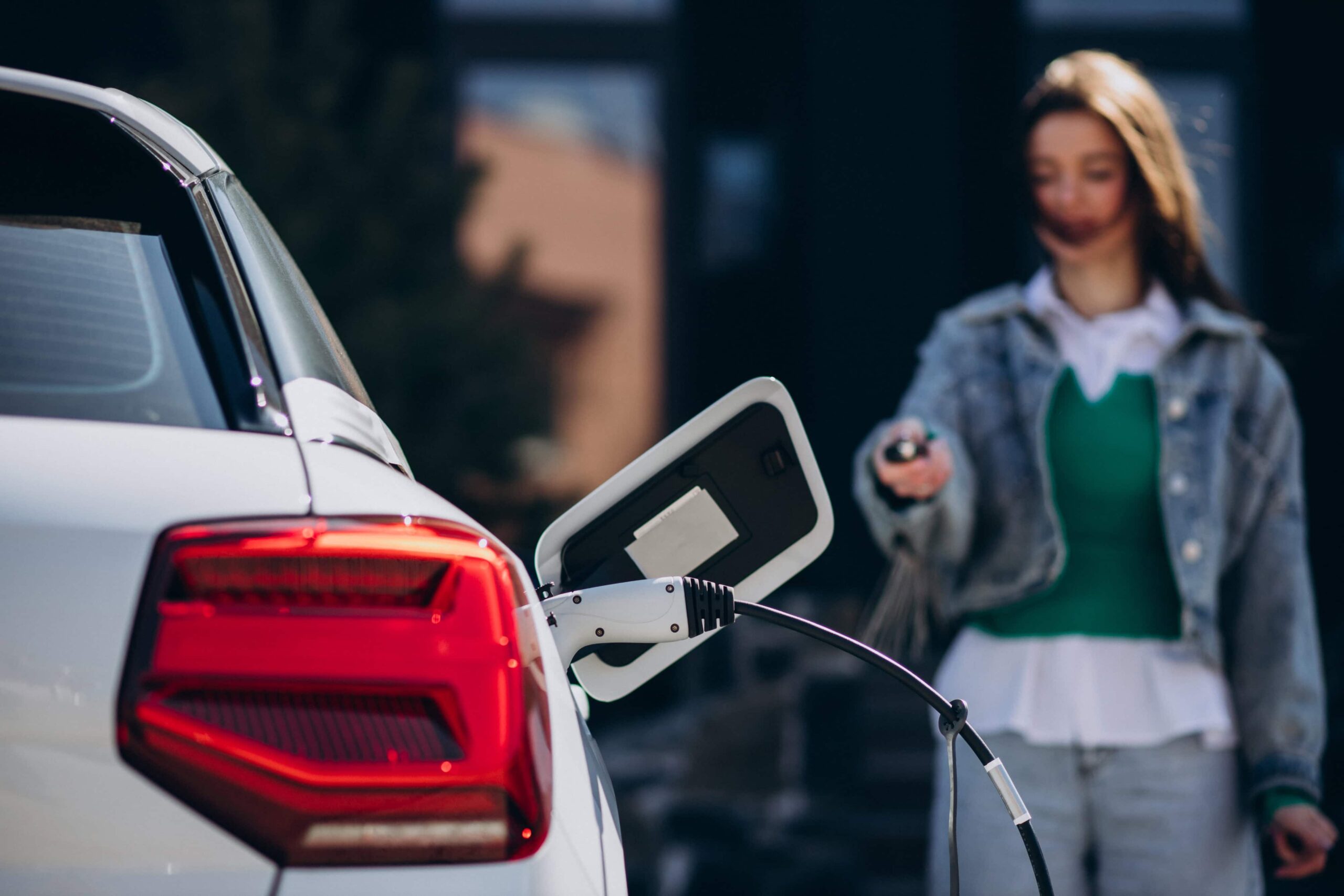 woman charging her electric car with charging pistol